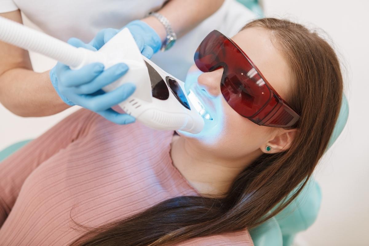 Mujer recibiendo un tratamiento de blanqueamiento dental profesional en una clínica dental.